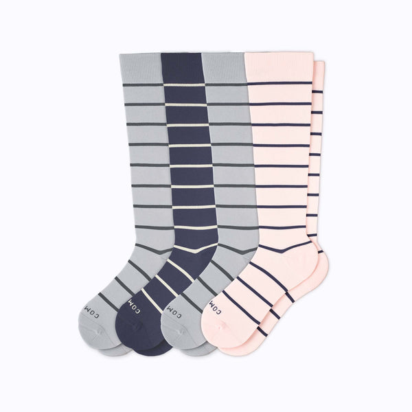 Four pairs of striped knee-high socks on a clean white background. The left pair is light gray with dark gray stripes and a gray toe/heel.