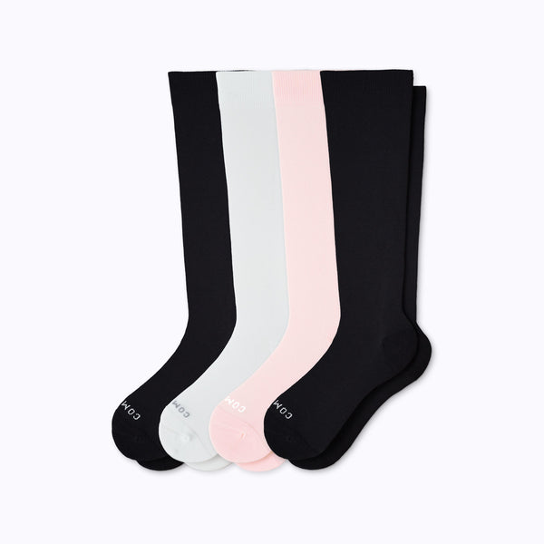 Set of four knee-high socks in black, white, and pink on a light gray background