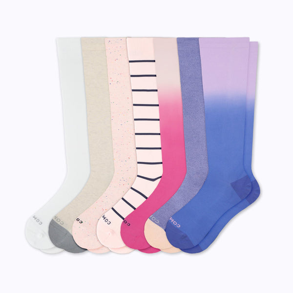 7 pairs of knee-high compression socks in whites, pinks and purples.