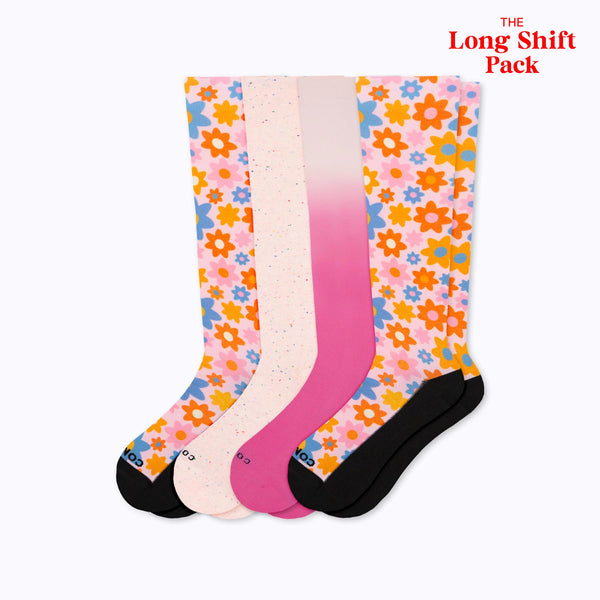 Three pairs of socks with floral patterns in pink, white, and black on a white background.