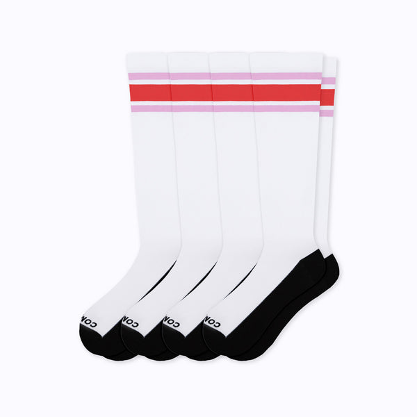 Four pairs of white crew socks with black toes and heels, featuring two horizontal stripes near the top in red and light pink.