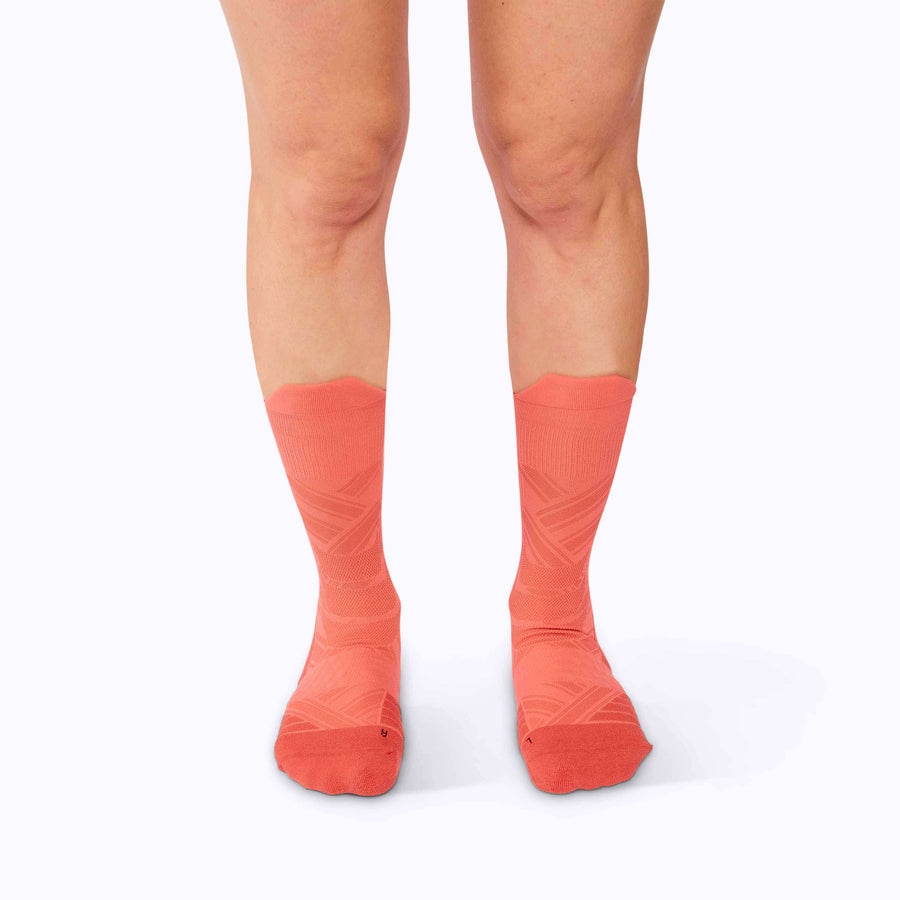 Front view of a pair of legs wearing an athletic crew compression socks coral solid