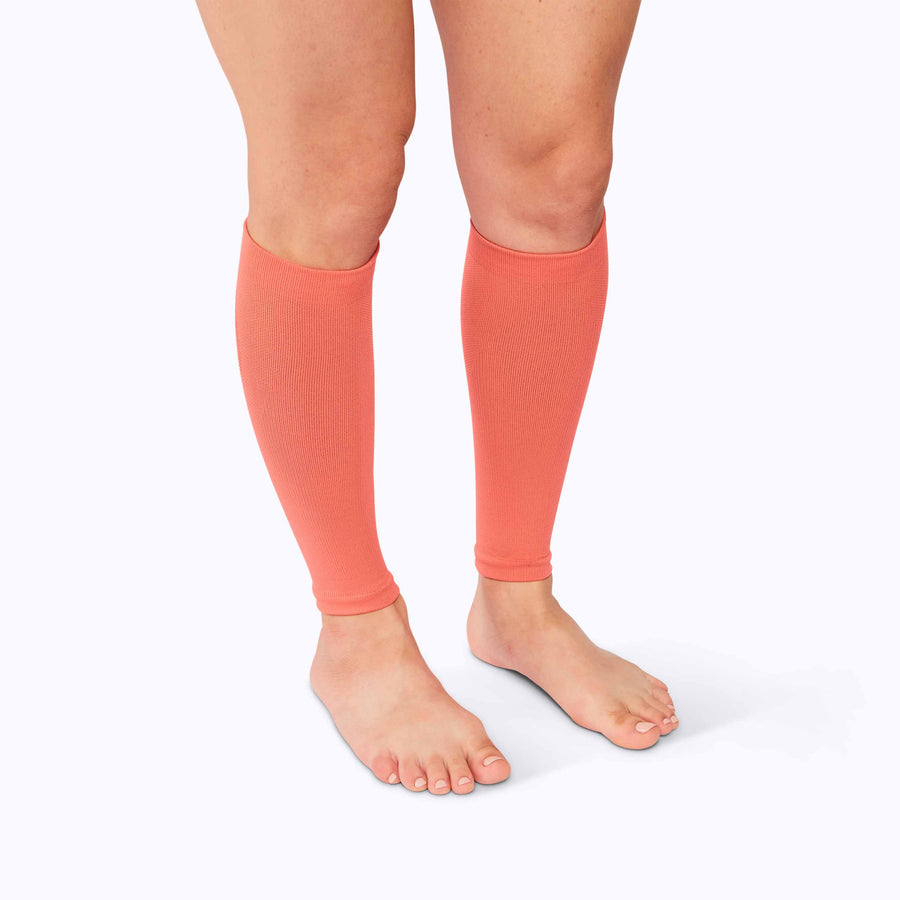 Side view of feet wearing a calf compression sleeve performance blend coral solid