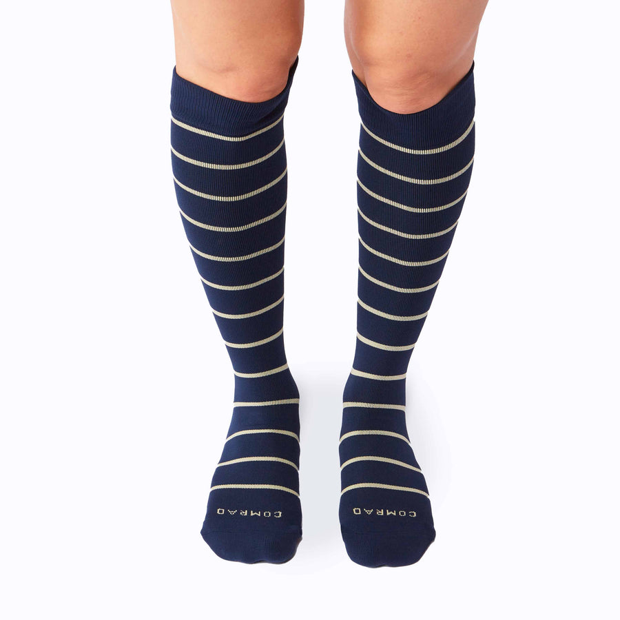 Front view of a pair of legs wearing nylon knee high compression socks in navy-sand stripes