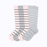 Set of four pairs of striped knee-high socks in pink and gray on a white background