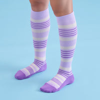 Purple and white striped knee-high socks on a person against a blue background