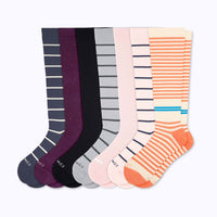 Seven pairs of knee-high socks in different colors and stripe patterns, arranged in a fan shape on a light gray background.