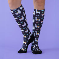 Knee-high socks with llama pattern worn by a person on a purple background