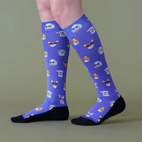 Blue knee-high socks with dog pattern worn by a person on a green background