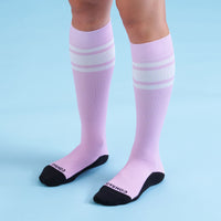 Pink knee-high socks with white stripes on a light blue background