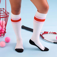 White knee-high socks with red and pink stripes worn by a person on a light blue background.