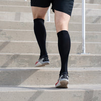 Person wearing black compression socks and running shoes on concrete steps