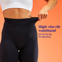 A close-up of a person wearing black high-rise ribbed leggings, pulling the waistband outward to demonstrate stretch. The person is cropped from the chest down against a solid orange background, with blue text on the right reading 'High-rise rib waistband' and 'No roll. No dig. No adjusting.'
