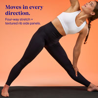 A woman in a white sports bra and black leggings poses in a yoga side stretch against a solid orange background, with blue text on the left 'Moves in every direction. Four-way stretch plus textured rib side panels.'