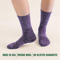 Purple crew socks worn by a person on a beige background with text about material and origin.