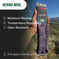 Hand holding a pair of Comrad Merino Wool compression socks with outdoor background