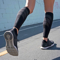 Person wearing black calf compression sleeves while running outdoors