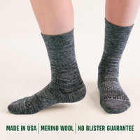 Gray merino wool socks worn by a person on a white background with branding text.