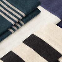 Close-up of folded blue and white striped fabric, black and beige patterned fabric on a neutral background