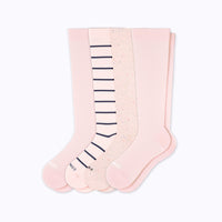 Set of four pairs of pink knee-high socks with different patterns on a light gray background