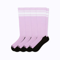 Four pairs of crew socks in light pink with two white stripes near the top and black heels, toes, and soles.