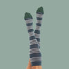 A person with their feet in the air showing Comrad Sock's striped, knee-high compression socks