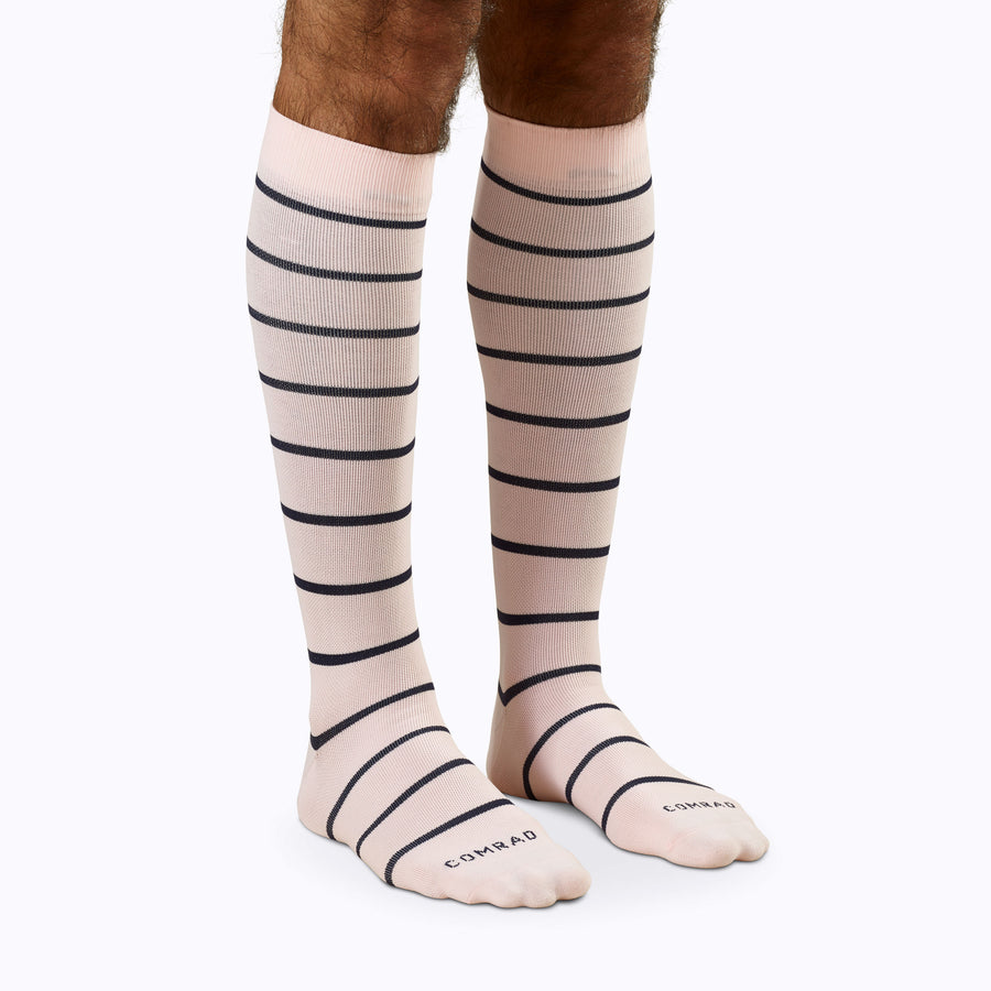 Front view of legs wearing a pair of knee high compression socks in rose-navy stripes
