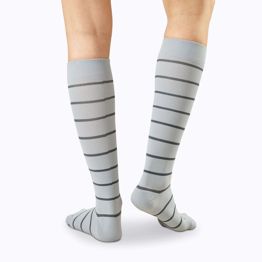 Back view of legs wearing a pair of knee high compression socks in grey-charcoal stripes
