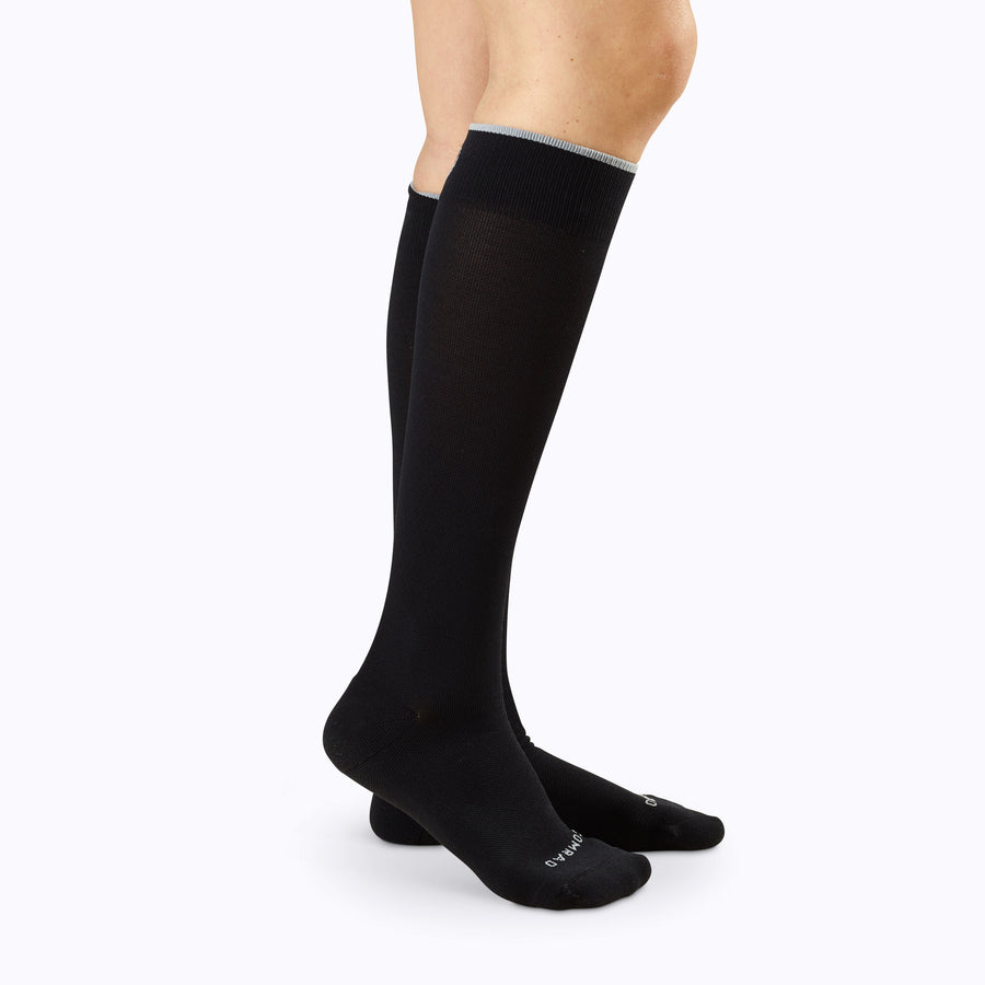 Side view of a pair of legs wearing nylon knee high compression socks in classic solid