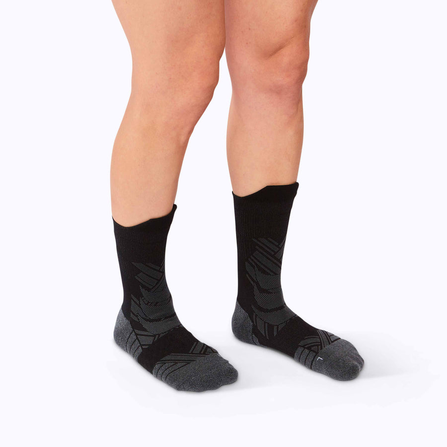 Side view of a pair of legs wearing an athletic crew compression socks black solid