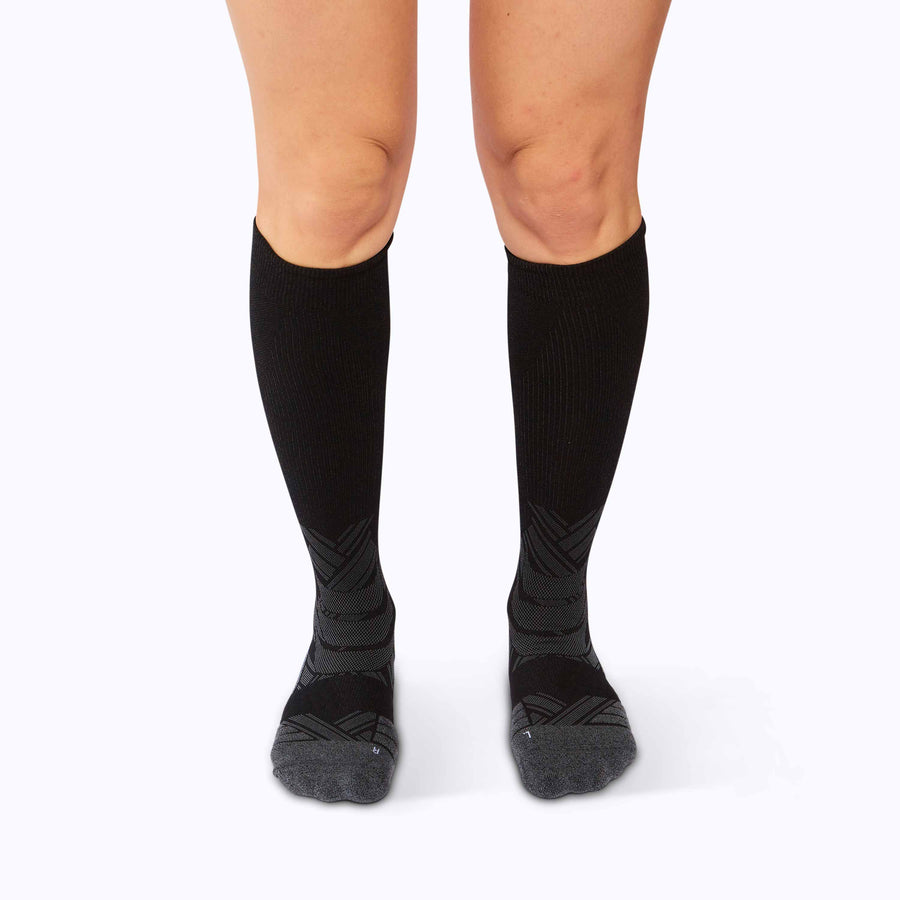 Front view of feet wearing an athletic knee high performance blend socks black solid