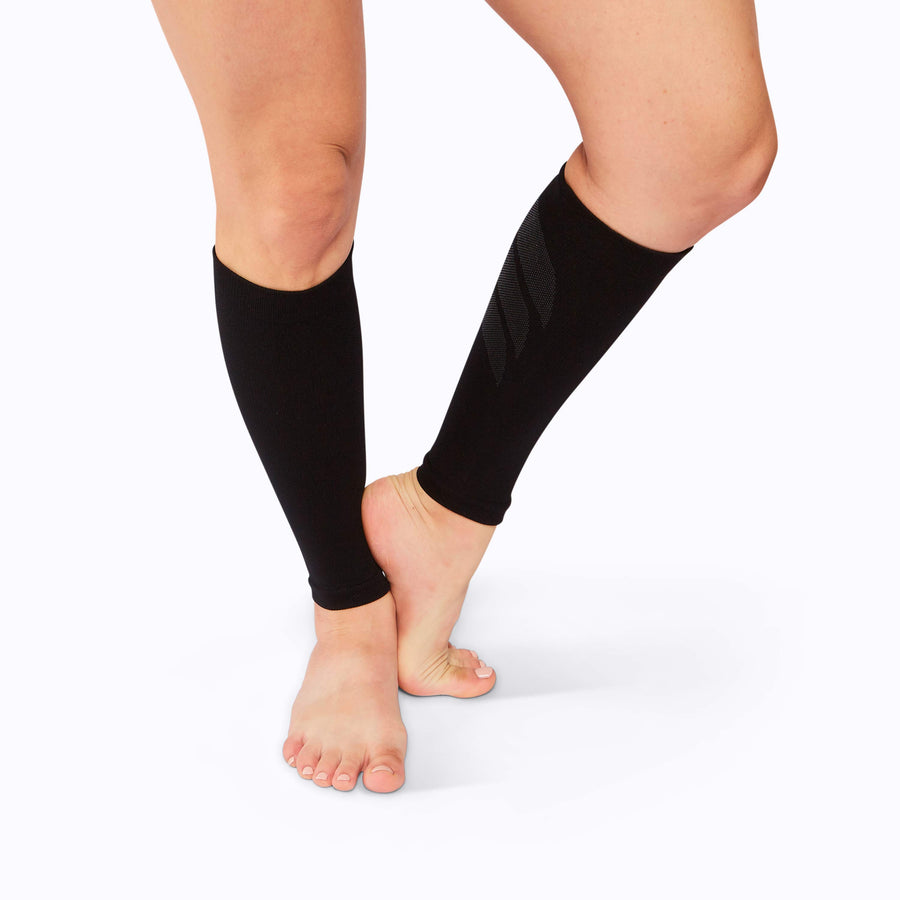 Front view of feet wearing a calf compression sleeve performance blend black solid