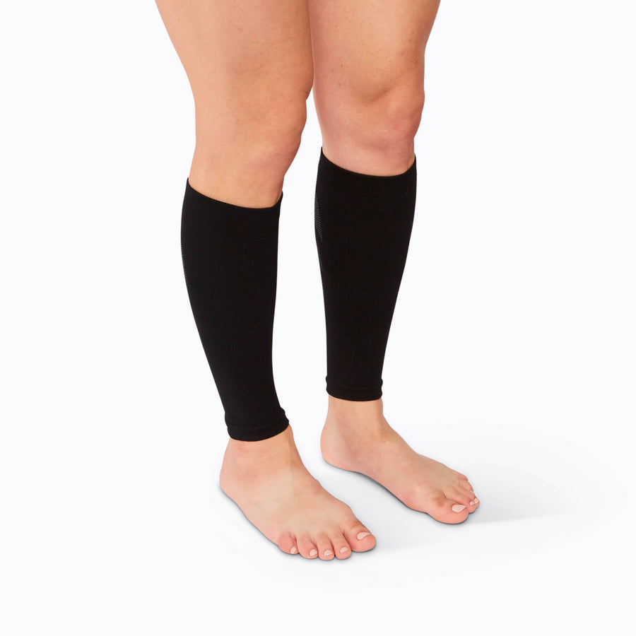 Side view of feet wearing a calf compression sleeve performance blend black solid
