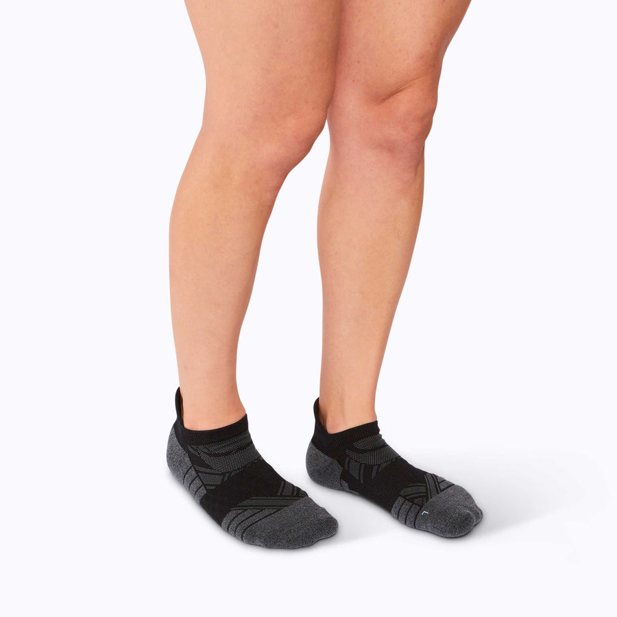 Side view of feet wearing a  performance blend ankle socks black solid