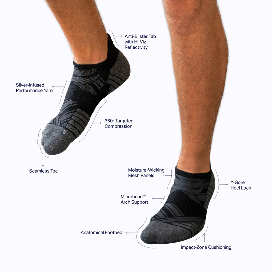 A pair of  feet wearing an athletic tab ankle socks black solid