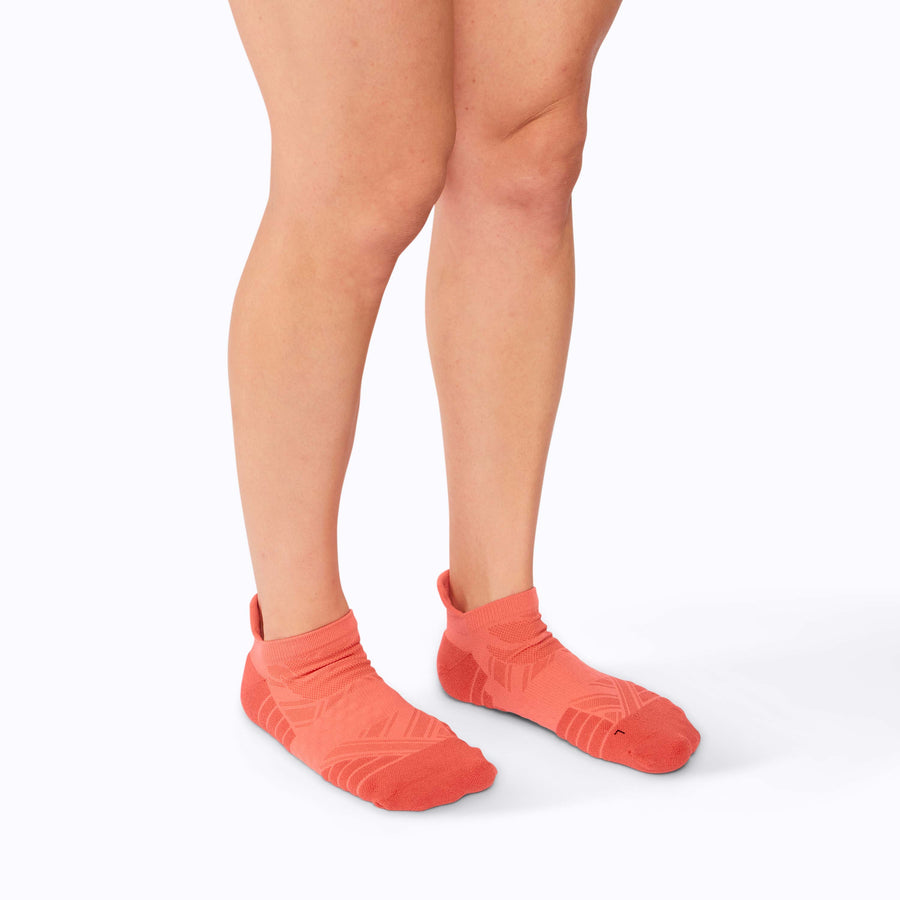 Side view of  feet wearing an athletic tab ankle socks coral solid