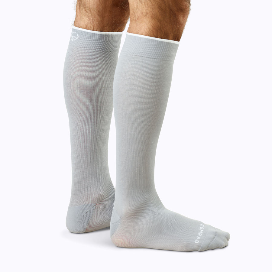 Back view of a pair of legs wearing nylon knee high compression socks in grey solid