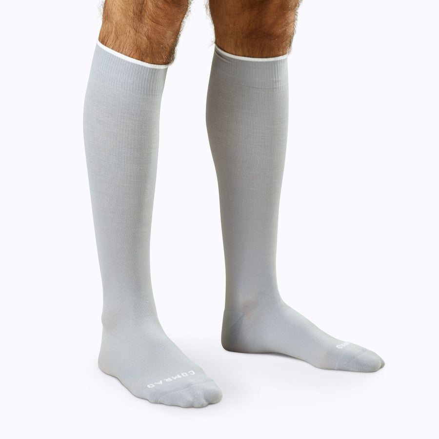 Side view of a pair of legs wearing nylon knee high compression socks in grey solid