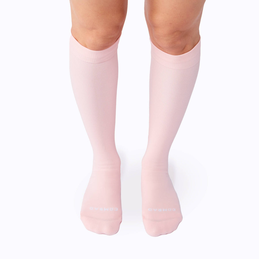 Front view of a pair of legs wearing nylon knee high compression socks in rose solid