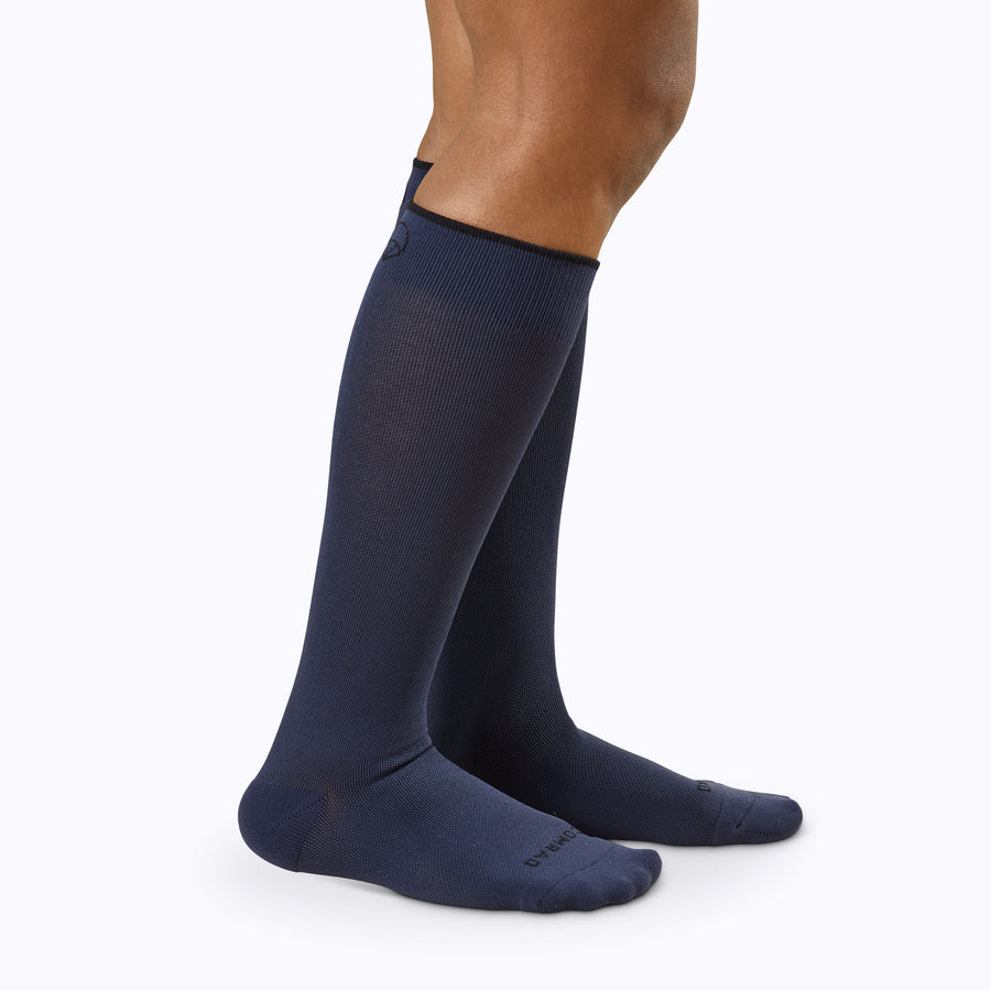 Side view of a pair of legs wearing nylon knee high compression socks in navy solid