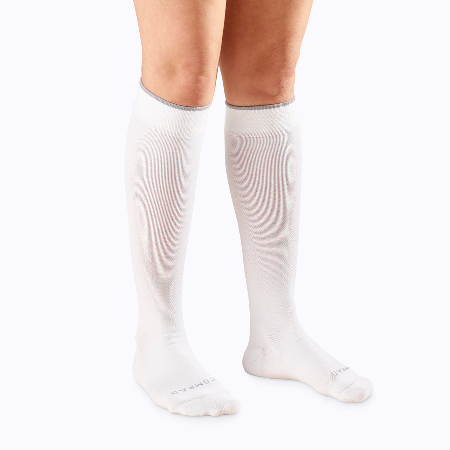 Front view of a pair of legs wearing nylon knee high compression socks in white solid