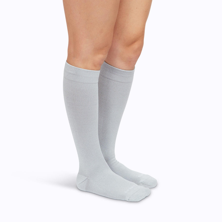 Side view of a pair of legs wearing nylon knee high compression socks in heather-grey solid